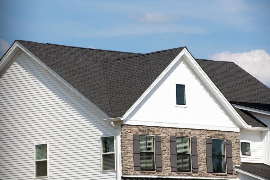 Stock image of residential home with brown rooftop and white siding